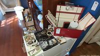 Overview of red jewelry box open with various necklaces, bracelets and loose items on top of white table