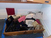 Wooden drawer containing an assortment of handbags and pouches