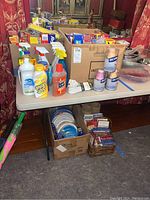 Overview of household cleaning products, disposable wraps, and bags arranged on table and in boxes.