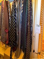 Multiple men’s ties hanging on a rack showing various patterns and colors, including paisley, stripes and geometric prints.