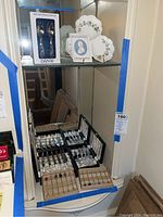 Dresser corner showing displayed boxed Dansk baby fork and spoon set, Wedgwood floral dish, and multiple sets of cutlery with mother of pearl handles.