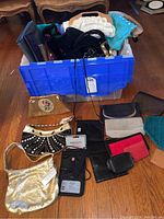 Overview image showing a blue storage bin filled with assorted purses, wallets, and clutches, along with several laid out on floor around it.