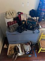 Overview of purses displayed on top of dresser and in box on floor
