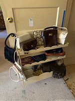 Full view of multiple purses and handbags on a rack including structured and fringe style bags, some with chain straps.