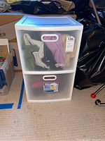 White plastic storage drawer unit with translucent drawers, filled with clothes.