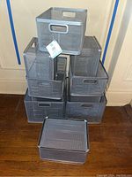 Nine silver metal mesh office storage boxes stacked and arranged showing two sizes.