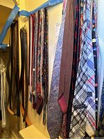 Photo showing a variety of men's neckties hanging vertically with visible different patterns and colors.