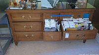 Full view of dresser showing three open drawers filled with papers and other contents, plus various items on glass top