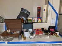 Full lot overview showing wooden box with matchbooks, vintage lighters, ashtrays, and various matchbooks laid out on a table.