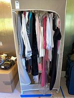 Full view of portable wardrobe rack filled with various women's clothing of different colors and styles.