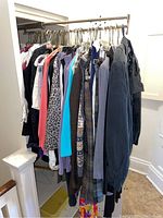 Wide view of women's clothes on hangers on a metal rack featuring different colors and patterns