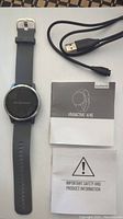 Garmin Vivoactive 4 smartwatch with charging cable and manuals laid out on surface, showing all included items.