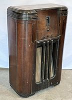 Angled view of the large antique Philco Model 16 radio showing dark solid wood cabinet with wear marks and speaker grille.