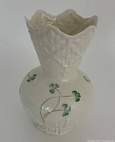 Front view of white Belleek vase showing shamrock design and scalloped rim