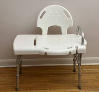 Front view of white shower seat with aluminum adjustable legs and one support arm.