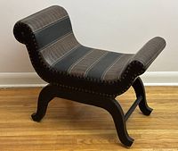Side angle of curved bench showing faux leather upholstery with nailhead trim, wood base and curved legs.