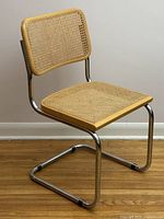 Front-right three-quarter view showing chrome cantilever frame, rattan seat and back