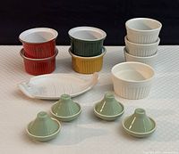 Full collection laid out showing four colored Emile Henry ramekins, four light green mini tagines, and white fish plate by Joyce Chen.