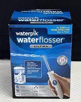 Front view of the Waterpik Water Flosser Ultra box, highlighting product and key benefits like plaque removal, six included tips, and a three-year warranty.