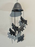 Photo of pewter wind chime with six cardinal bird chimes hanging from a conical bell-shaped top against a white background. Birds are detailed and textured on branches.
