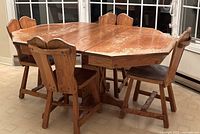 Solid oak wood dining table with four chairs shown with table extended using one leaf. Table is octagonal with visible wood grain and medium brown finish.
