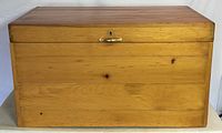 Front view of closed solid pine storage chest showing smooth wood finish and brass handle.