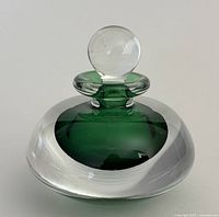Front angle view of the studio glass perfume bottle showing the green core and clear glass over-layer with round stopper.