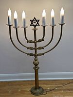 Full view of the vintage brass Menorah standing lit, showcasing the electric candle lights and Star of David centerpiece