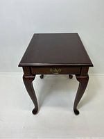 Front view of the mahogany end table showing single drawer with brass handle and Queen Anne style cabriole legs.