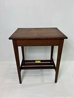 Front view of the antique solid wood end side table showing the tapered legs and stretcher bars.