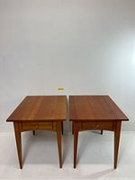 Frontal view of both cherry wood end tables side by side against white background