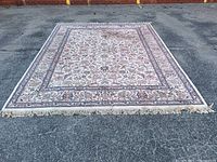 Full view of the vintage Karastan rug laid out on pavement showing overall design, border, and fringe.