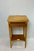 Front view of the chestnut colored wood book stand showing drawer and shelf.