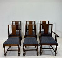Front view of six dining chairs, one armchair and five side chairs, showing wooden frames and blue fabric upholstered seats.