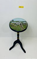 Full view of wooden tripod candle stand with hand-painted seaside landscape top.