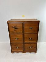 Front view of vintage wooden cabinet showing six drawers with ornate metal handles and top pull-out tray