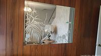 Rectangular wall mirror measuring approximately 48 x 36 inches with detailed etched bamboo and floral designs on glass surface. Mirror is hung on wall with brown wood paneling as background.