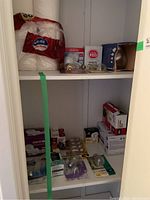 Closet shelf with packs of toilet paper, boxed light bulbs, and light bulbs in plastic packaging