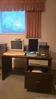 Overall view of desk with computer tower, monitor, printer, shredder and supplies on top