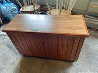 Front view of the cedar cabinet showing vertical wood panel doors on wheels, doors closed.