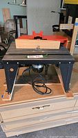 Front view of Craftsman router table with wooden fence and power cord visible underneath.