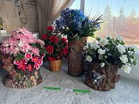Four silk flower arrangements in animal-themed containers on a light carpeted surface near window light.