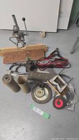 Overview of the lot showing dress press assembly, jumper cables, grinder wheels and other tools on a grey floor.