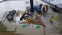 Full view of lot on white surface showing variety of clamps, scissors, clothespins, tape, and flashlight