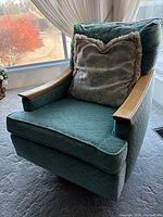Front view of vintage steel blue swivel rocking chair with cushion showing fabric pattern and wooden armrests.