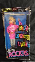 Front view of Barbie doll inside original box, showing pink outfit and hair style, box worn at top