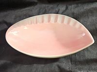 Top view of leaf-shaped pink ashtray showing smooth glossy surface and ridged side.