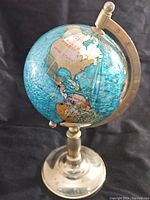 Photo showing the globe facing North America, mounted on its brass base with the meridian degree indicators visible.