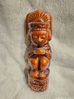 Full front view of the vintage ceramic tiki decanter showing the detailed figure with headdress and seated posture.