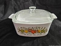 Full view of vintage Spice of Life casserole dish with clear glass lid, showing fruit and herb design on side.